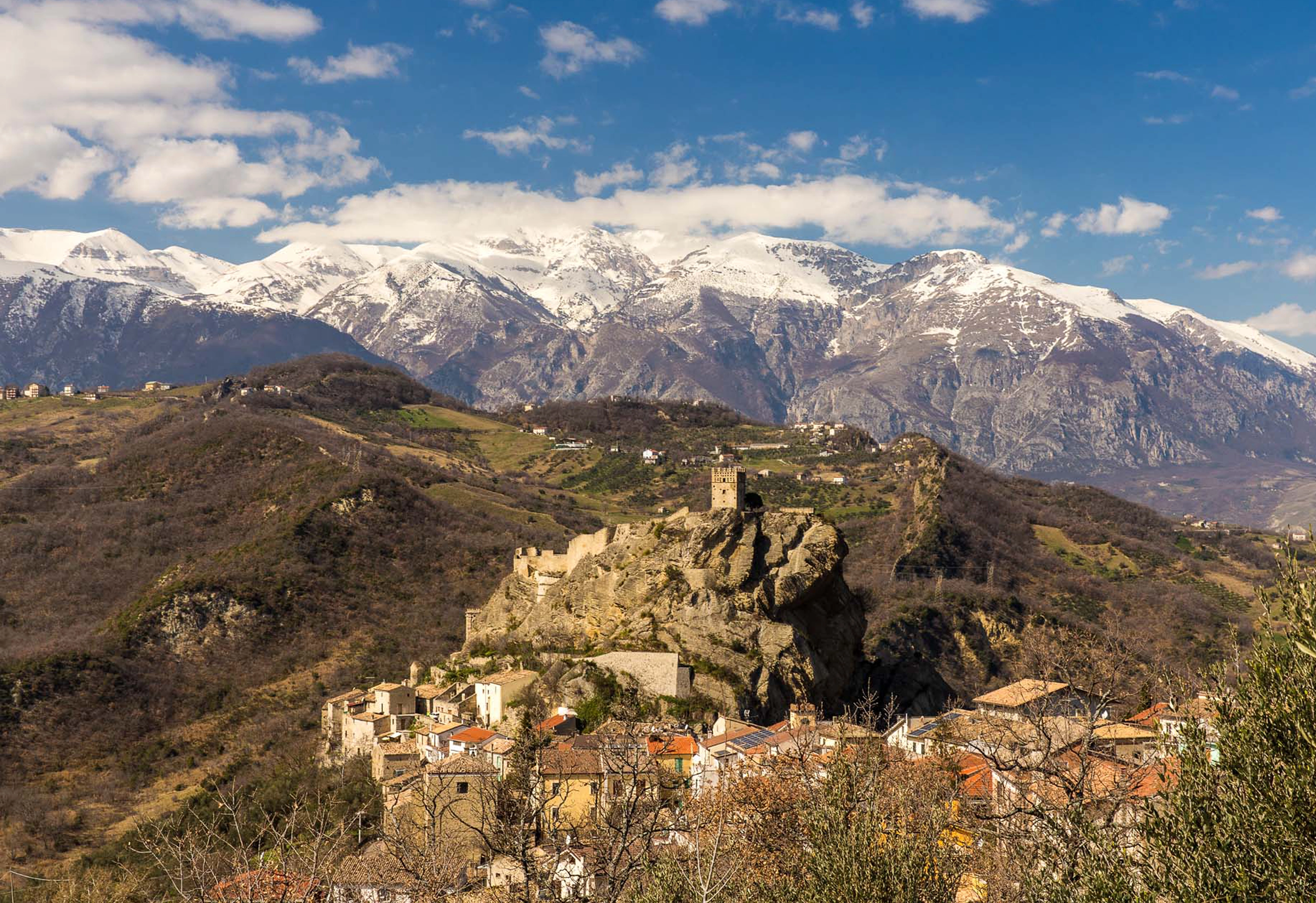 Small observatory houses in a hillside landscape below a castle.